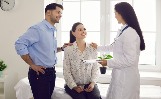 A male and female couple are pictured consulting with a female doctor about starting a family.