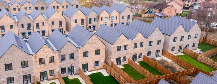 Aerial view of rows of new build modular terraced houses in the UK with characterless design for first-time buyers.