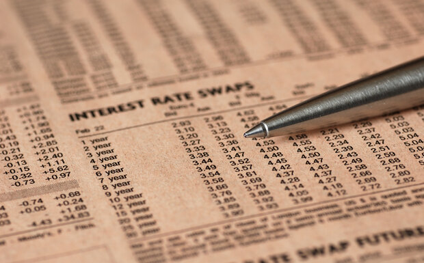 Table of SWAP rates printed in a newspaper with a pen laid across the top.