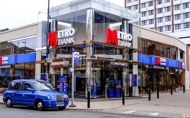 The outside of a branch of Metro Bank in London with a blue black cab sat outside it.