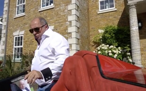 Glen Armstrong, property developer, getting into a red Ferrari sports car outside his property.