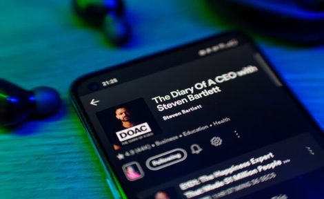 A mobile phone showing 'The Diary of a CEO' podcast by Steven Bartlett.