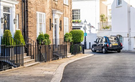 A small residential street in Belgravia, London, with a black taxi in the distance.