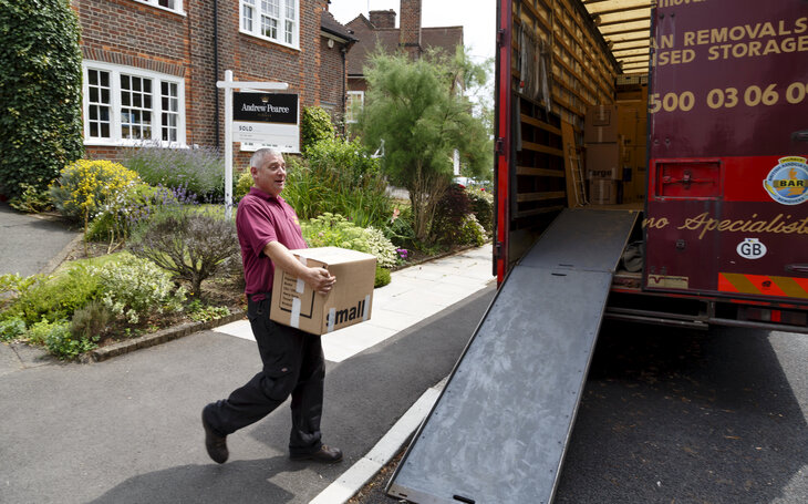 A moving van is pictured in a treelined road and a removal man is loading it up after tenants have been forced to move due to the property being sold. 
