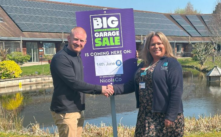 Matt Nicol, MD of Nicol & Co., with Ria Simon, community fundraiser at St Richard’s Hospice and Garage Sale sign