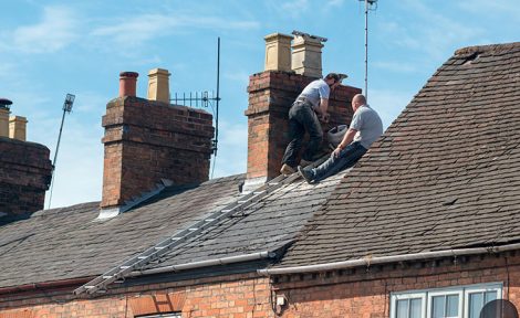 Two men fixing a roof
