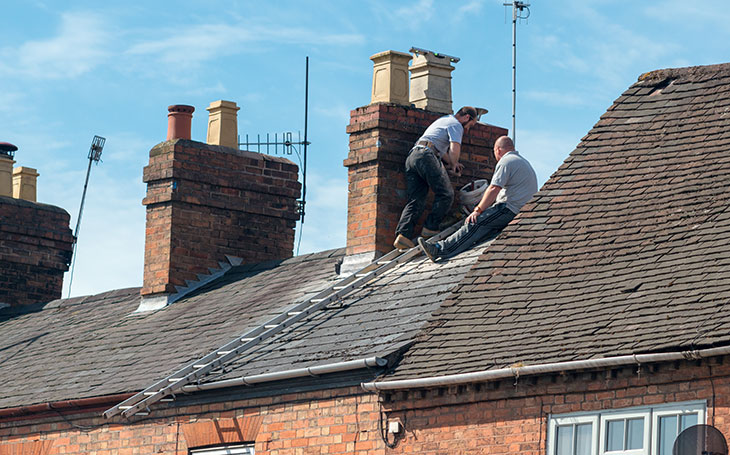 Two men fixing a roof